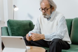 An Elderly Man Sitting in a Couch Holding a Pulse Oximeter