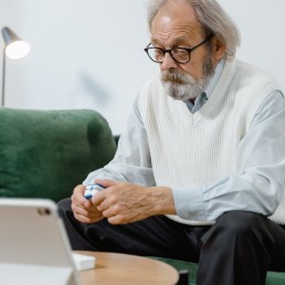 An Elderly Man Sitting in a Couch Holding a Pulse Oximeter