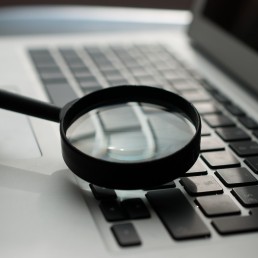 magnifying glass near gray laptop computer