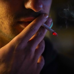 a man smoking a cigarette in the dark