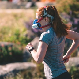 a woman wearing a mask and running in a field